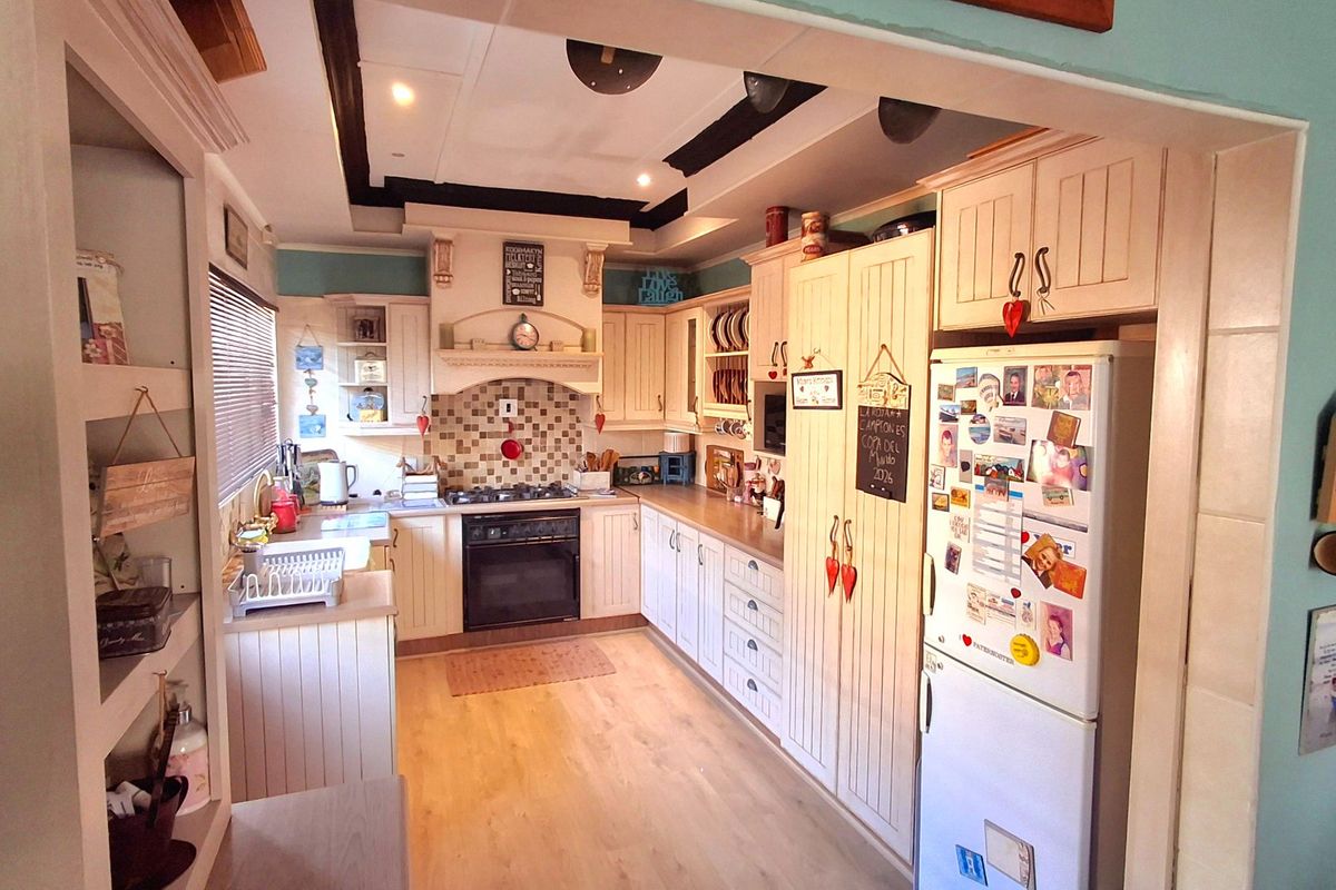 A cozy, country-style kitchen featuring built-in cabinetry, a tiled splashback, integrated oven, and a distinctive recessed ceiling design.
