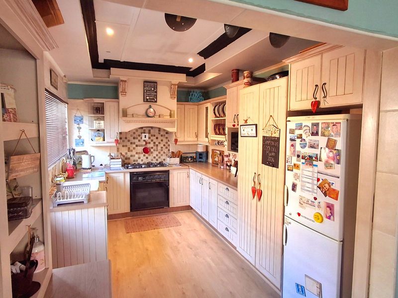 A cozy, country-style kitchen featuring built-in cabinetry, a tiled splashback, integrated oven, and a distinctive recessed ceiling design.