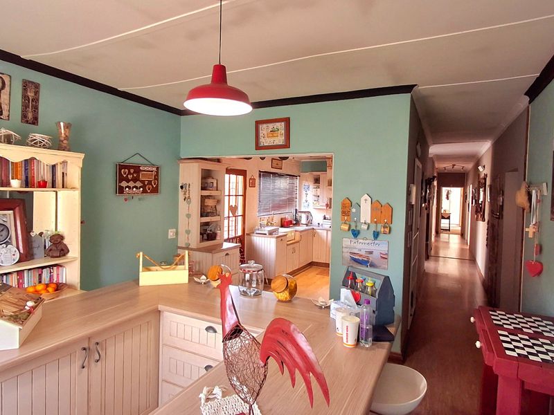 Open plan living area featuring a kitchen island with built-in cabinetry, leading into a secondary kitchen space and a long hallway.