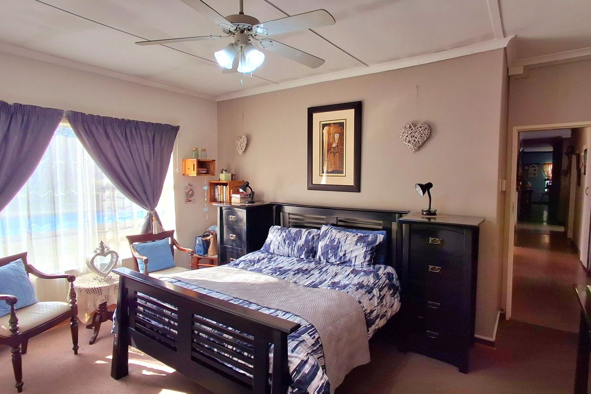A well-lit bedroom featuring a ceiling fan and neutral wall tones, offering a comfortable and functional living space.