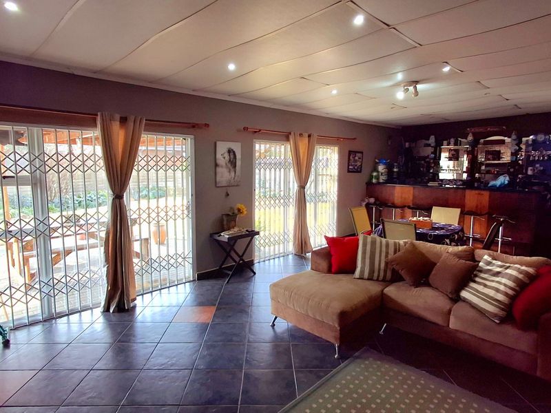 Spacious living area featuring tiled flooring, recessed lighting, and a built-in bar, with direct access to the outdoor patio through sliding glass doors.
