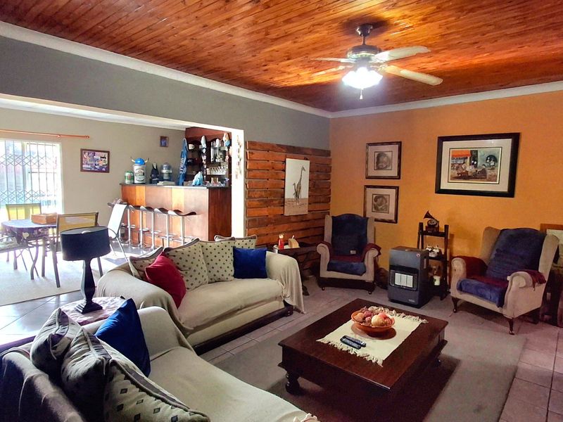Open plan living area featuring a timber ceiling, ceiling fan, and a built-in bar, with tiled flooring and access to an outdoor patio area.