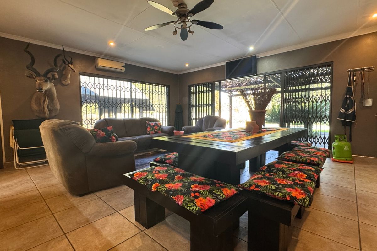 Spacious living area featuring tiled flooring, a ceiling fan, split-system air conditioning, and large sliding doors with security gates leading to the outdoors.