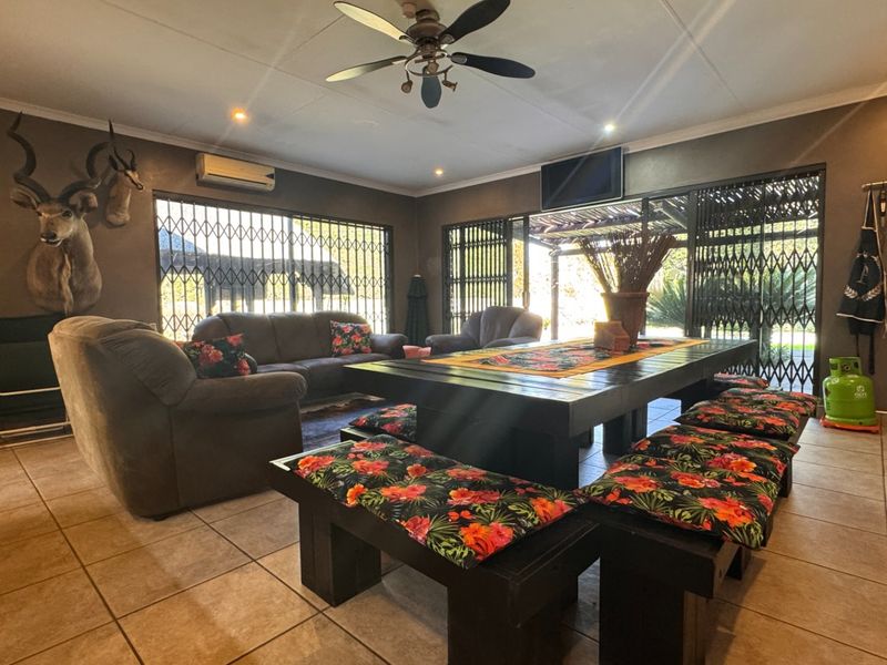 Spacious living area featuring tiled flooring, a ceiling fan, split-system air conditioning, and large sliding doors with security gates leading to the outdoors.
