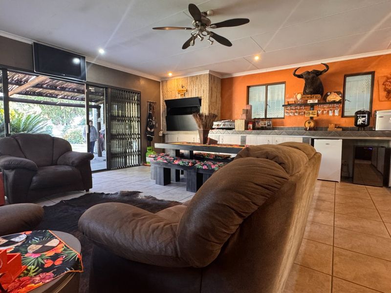 Spacious open-plan living area featuring a built-in fireplace, tiled flooring, and direct access to an outdoor patio through sliding glass doors.