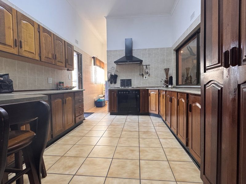 A functional kitchen featuring traditional wooden cabinetry, ceramic tile flooring, and a built-in oven with an extractor fan.