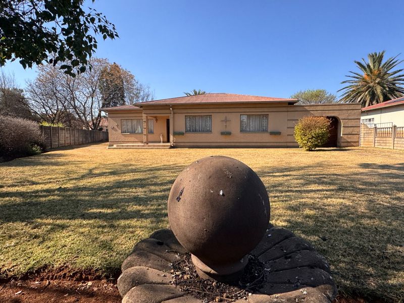 A view of the rear exterior of the house featuring a brick facade, corrugated roof, and a large garden with a stone water feature.