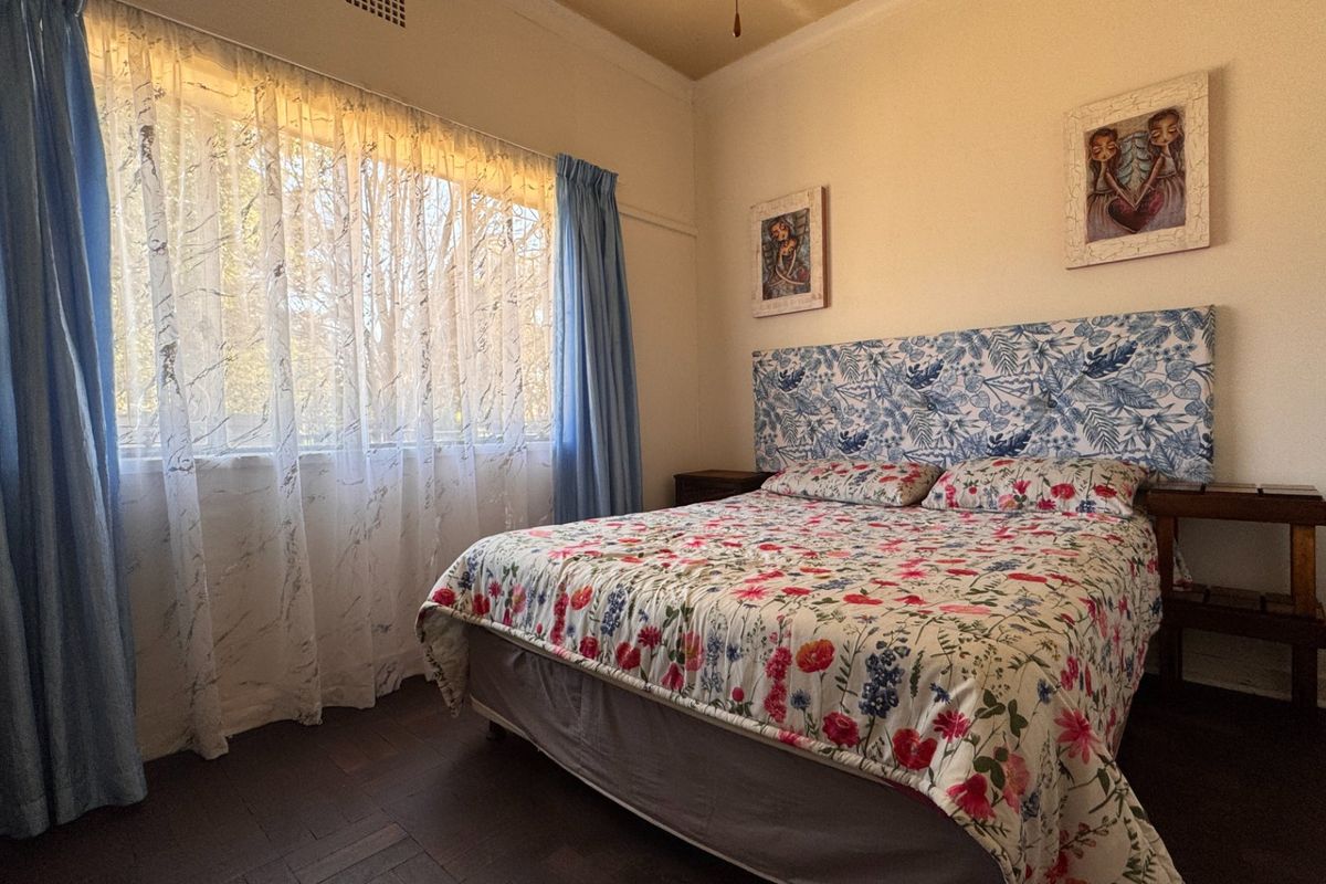 A well-lit bedroom featuring timber flooring and a ceiling fan, offering a comfortable and functional space.
