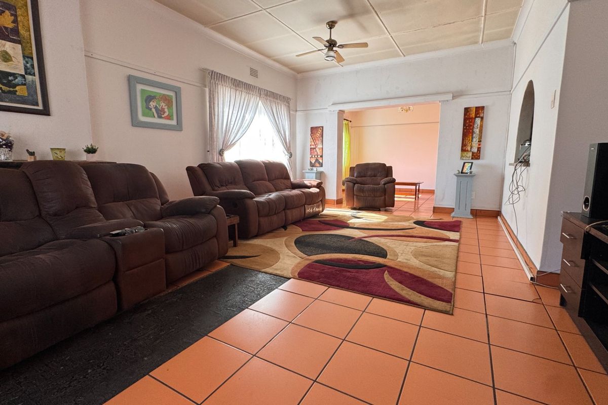Spacious living room featuring tiled flooring, a ceiling fan, and an open archway leading to an adjacent area.