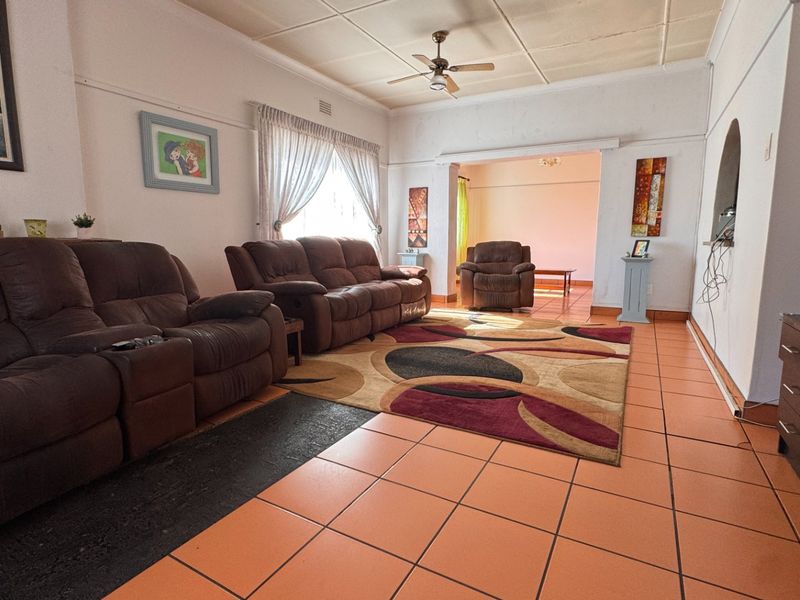 Spacious living room featuring tiled flooring, a ceiling fan, and an open archway leading to an adjacent area.