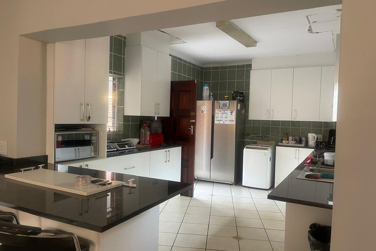 Functional kitchen featuring white cabinetry, dark granite countertops, tiled backsplash, and a breakfast bar, with some visible ceiling maintenance required.