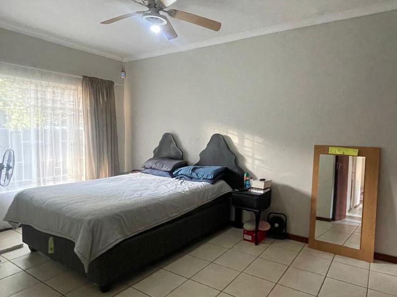 A spacious bedroom featuring tiled flooring and a ceiling fan, offering a neutral canvas for personalization and updates.