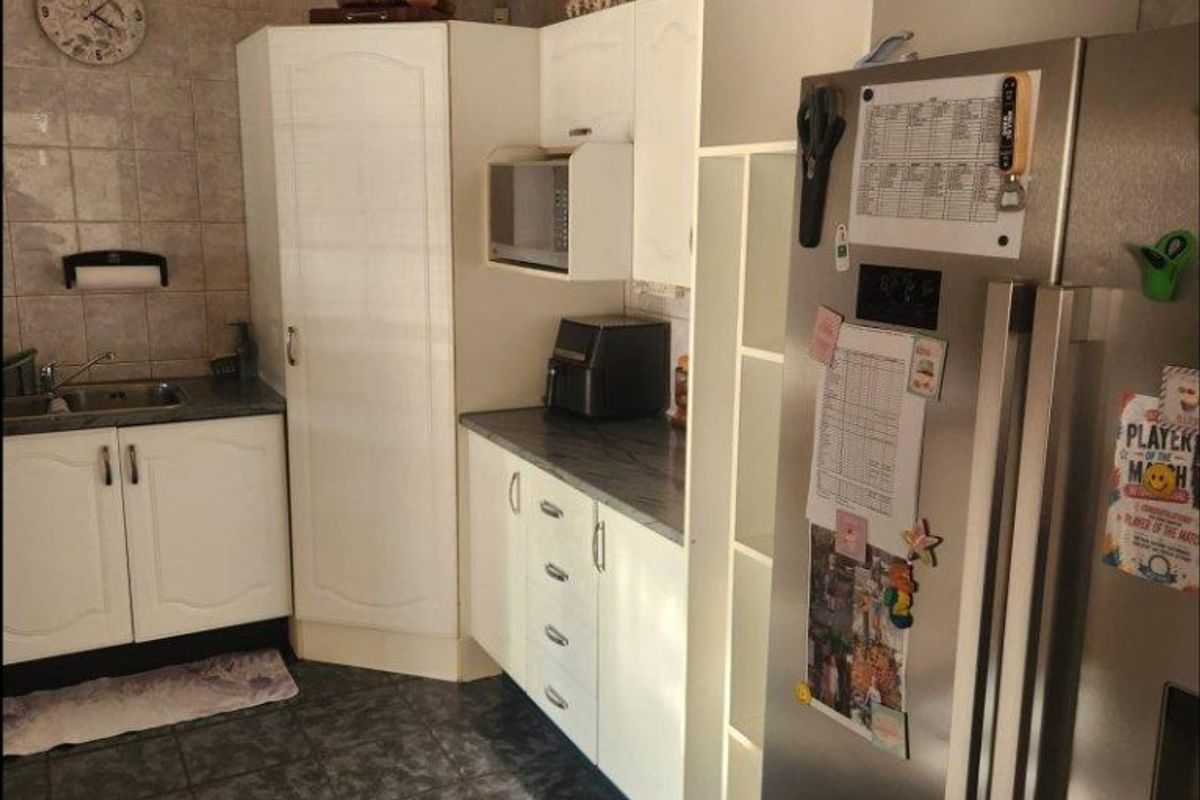 A functional kitchen featuring white cabinetry, laminate countertops, a stainless steel sink, and tiled finishes throughout.