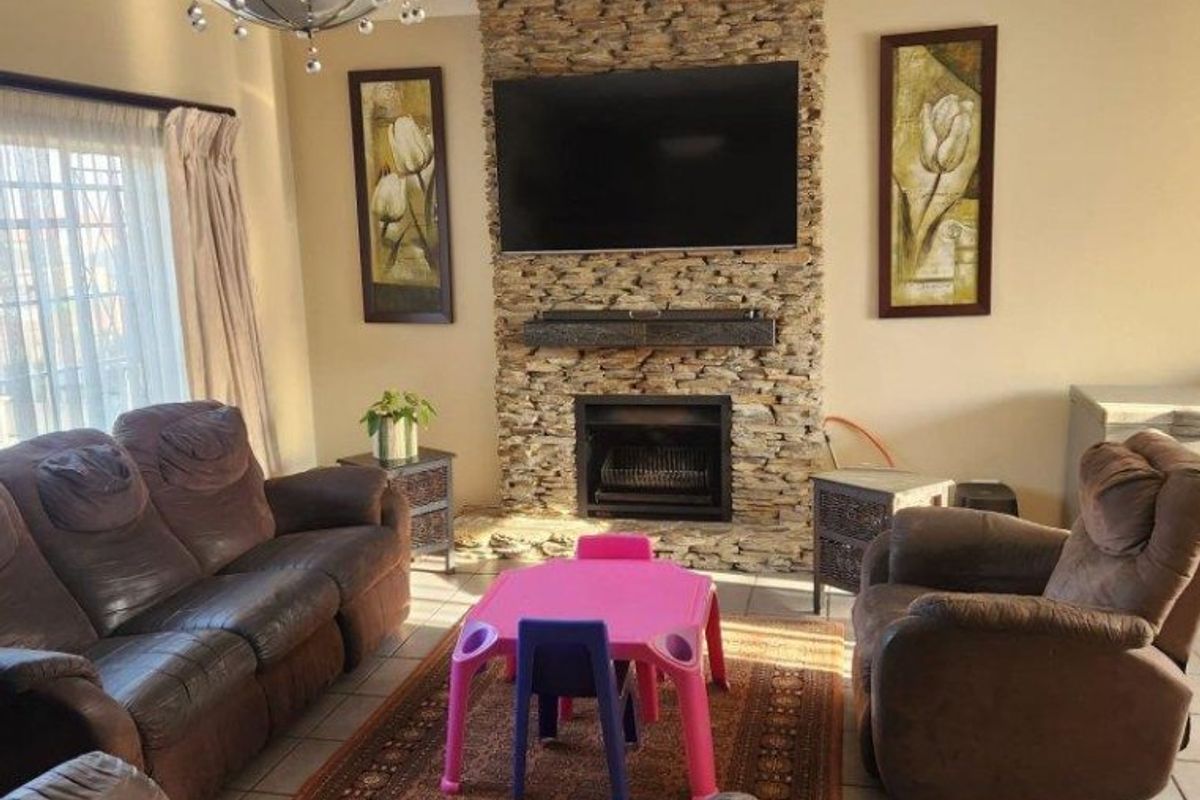 A comfortable living room featuring a prominent stone-clad fireplace and tiled flooring, providing a warm and inviting space for relaxation.