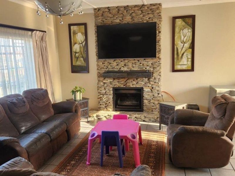 A comfortable living room featuring a prominent stone-clad fireplace and tiled flooring, providing a warm and inviting space for relaxation.