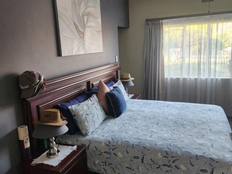 A bedroom featuring dark accent wall, window with security bars, and coving detail.