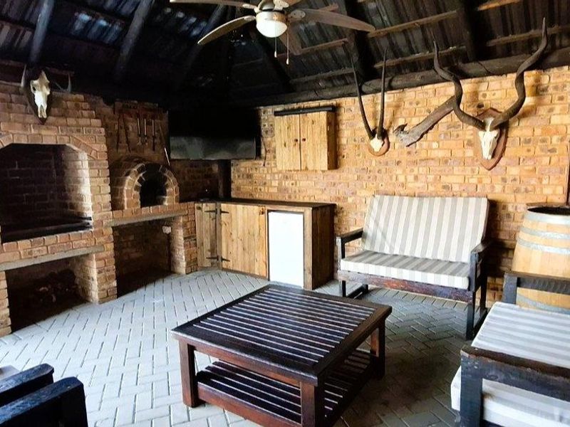 Covered outdoor entertainment area featuring a brick fireplace, built-in pizza oven, exposed timber roof structure, and durable brick paving.
