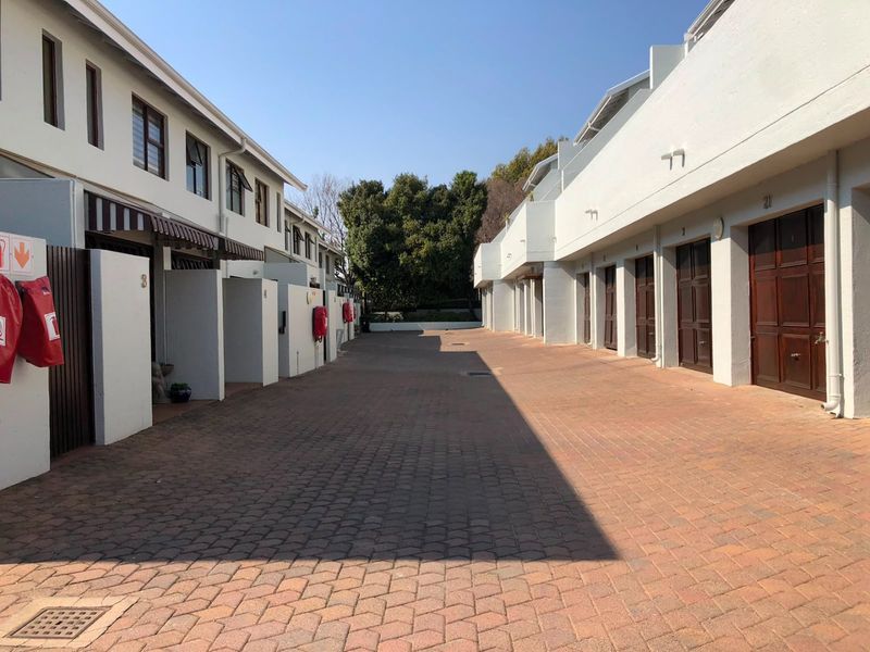 A view of the townhouse complex driveway featuring paved surfaces, multiple garage access points, and exterior wall-mounted fire safety equipment.