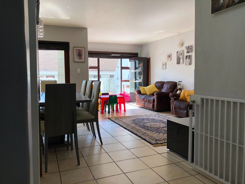 Open-plan living and dining area featuring neutral tiled flooring and large sliding doors providing access to the outdoor space.