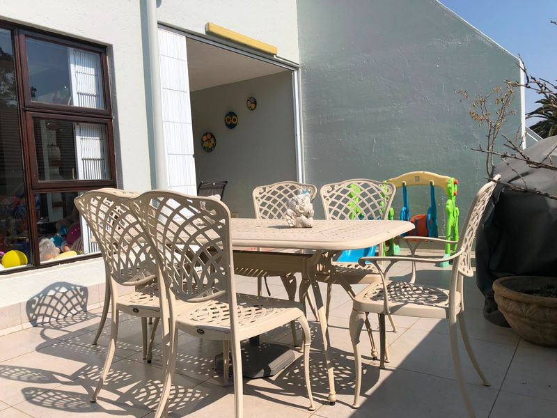 A paved outdoor patio area featuring a sliding door entrance, providing a functional space for outdoor dining and relaxation.