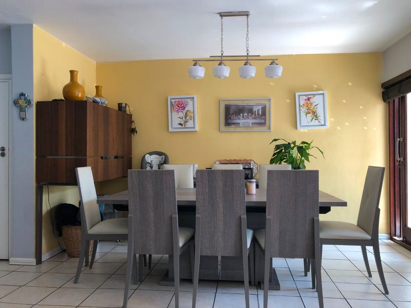 A dining room featuring ceramic tile flooring, a modern pendant light fixture, and a sliding glass door providing access to the exterior.