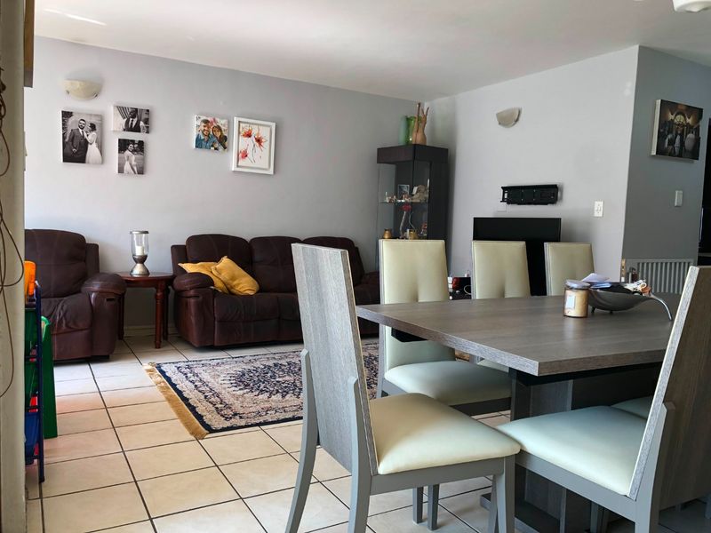 Open plan living and dining area featuring ceramic tiled flooring and wall-mounted lighting fixtures.