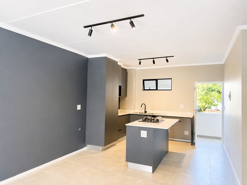 Modern kitchen featuring dark grey cabinetry, a central island with a built-in gas cooktop, sleek finishes, and direct access to an outdoor area.