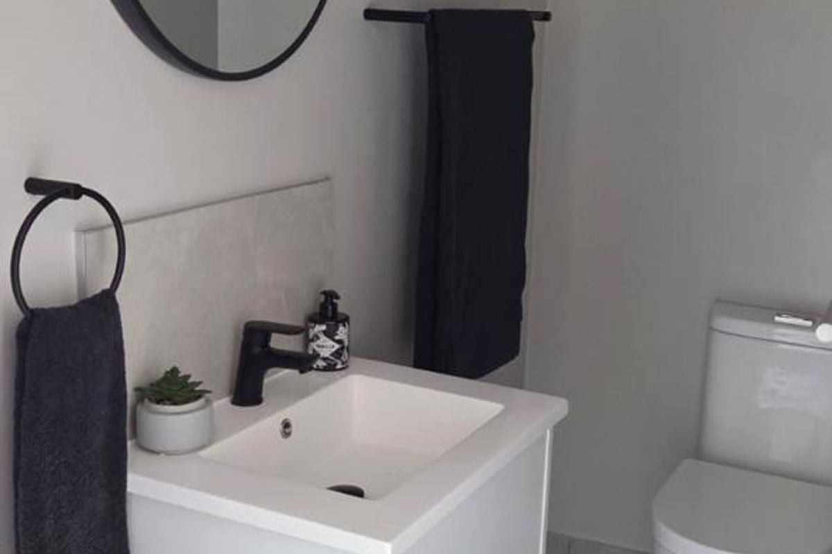 A modern, well-maintained bathroom featuring a wall-mounted vanity with a black mixer tap, a sleek basin, and a contemporary toilet.