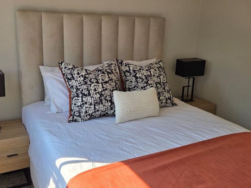 A well-maintained bedroom featuring a neutral upholstered headboard and clean, modern finishes.