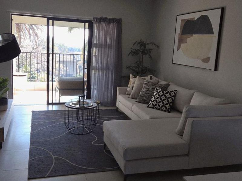 A well-lit living room featuring tiled flooring and a sliding glass door that provides direct access to an outdoor balcony area.