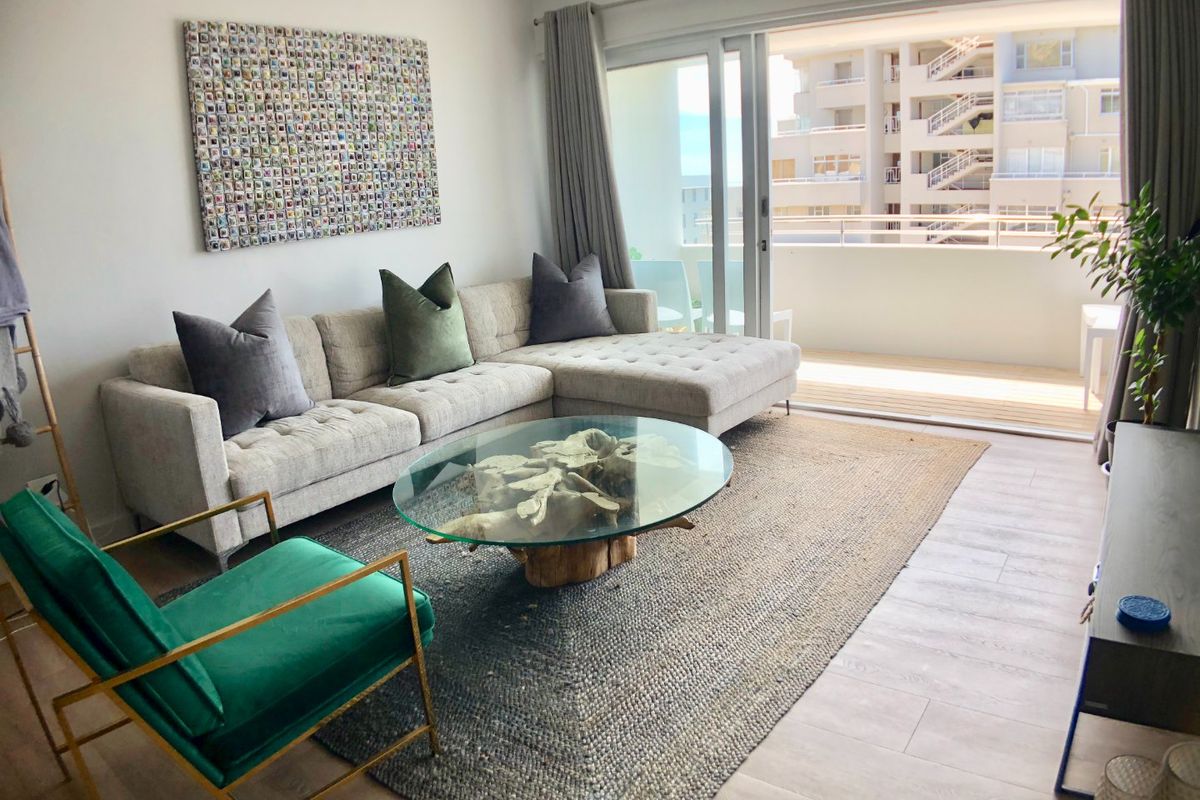 A bright and modern living room featuring laminate flooring and large sliding glass doors that open onto a private balcony.