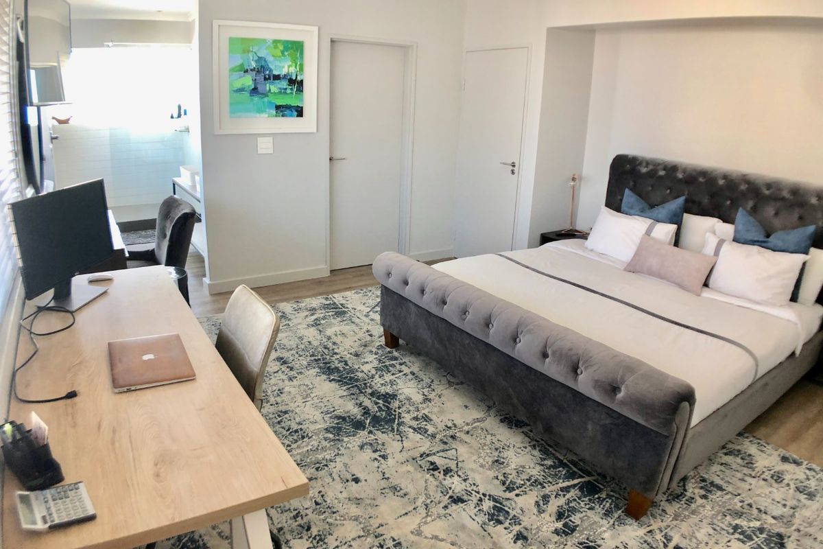 Spacious bedroom featuring laminate flooring, a recessed alcove for the bed, and an adjoining en-suite bathroom area.