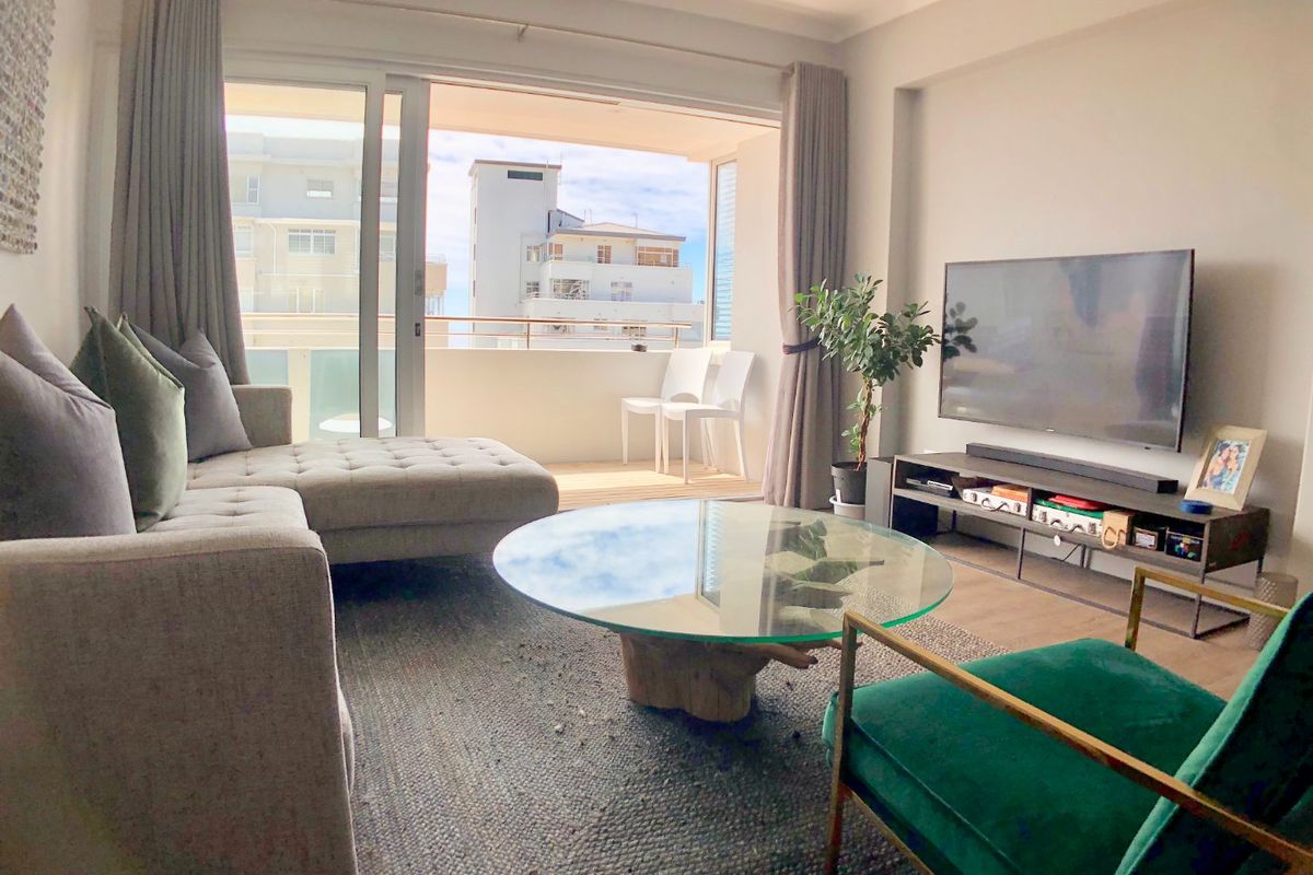 A bright and modern living room featuring large sliding glass doors that open onto a private balcony, providing ample natural light.
