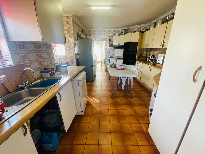 A functional kitchen featuring dated cabinetry, tiled splashbacks, and tiled flooring, offering significant potential for a modern renovation.