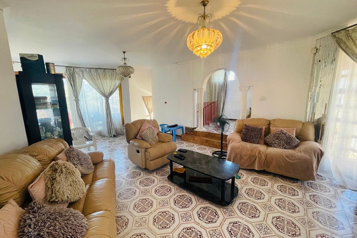 Spacious living room featuring decorative archways, ornate pendant lighting, and patterned ceramic floor tiles, offering a unique architectural layout.
