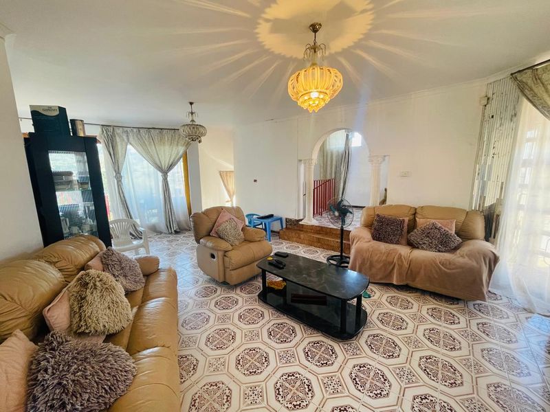 Spacious living room featuring decorative archways, ornate pendant lighting, and patterned ceramic floor tiles, offering a unique architectural layout.