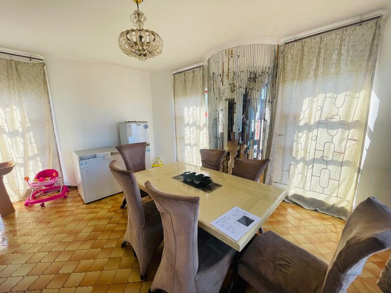 Dining room featuring a decorative chandelier, mirrored wall accent, and patterned floor tiles, offering a distinct space for formal meals.