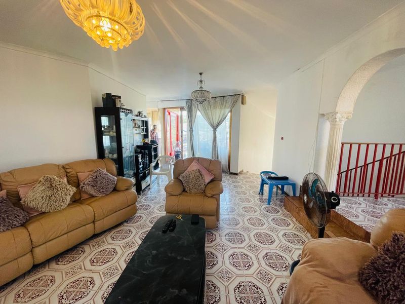 Spacious living area featuring decorative archways, ornate columns, and patterned ceramic tile flooring, offering a dated aesthetic with potential for modern updates.