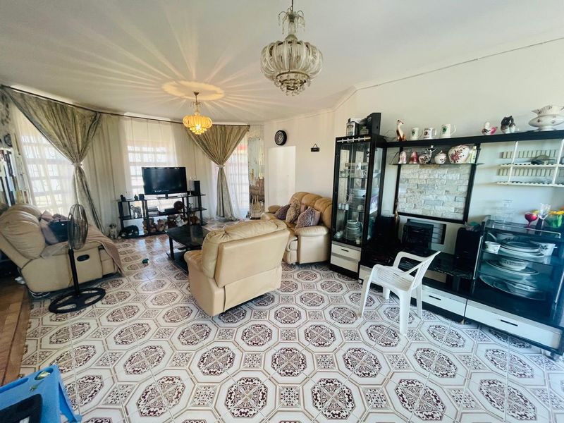 A spacious living room featuring patterned ceramic floor tiles and decorative ceiling lighting, offering a functional layout for relaxation and entertainment.