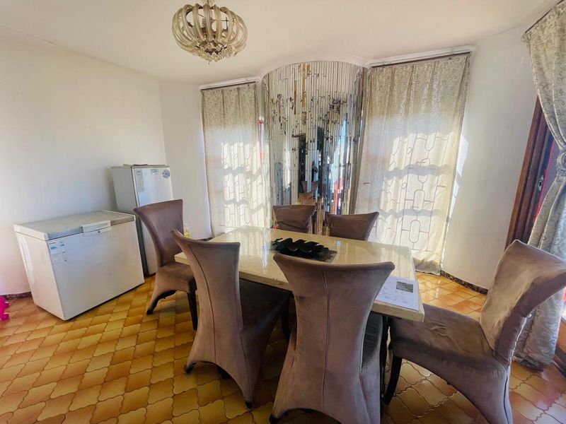 Dining room featuring a central light fixture, mirrored wall accent, and tiled flooring, offering a functional space for family meals.