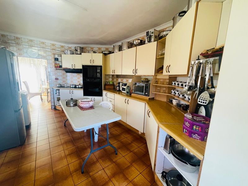 A functional kitchen featuring extensive built-in cabinetry, laminate countertops, and tiled finishes, offering a dated aesthetic with potential for modern renovation.