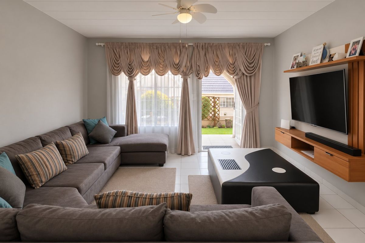 A well-maintained living room featuring tiled flooring, a ceiling fan, and a built-in media console, with direct access to an outdoor patio area.