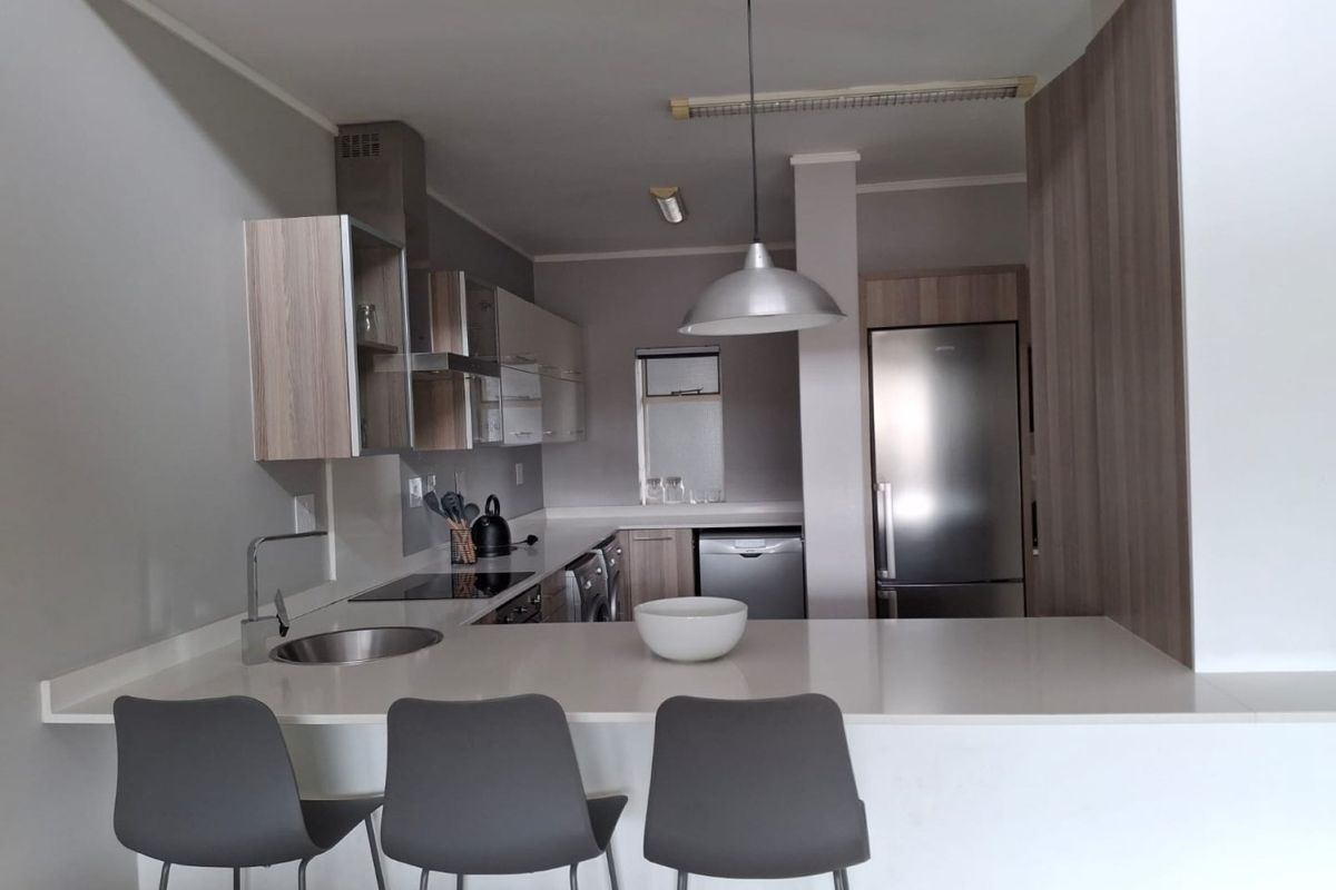Modern kitchen featuring sleek cabinetry, stone countertops, integrated appliances, and a breakfast bar with pendant lighting, creating a functional and contemporary cooking space.