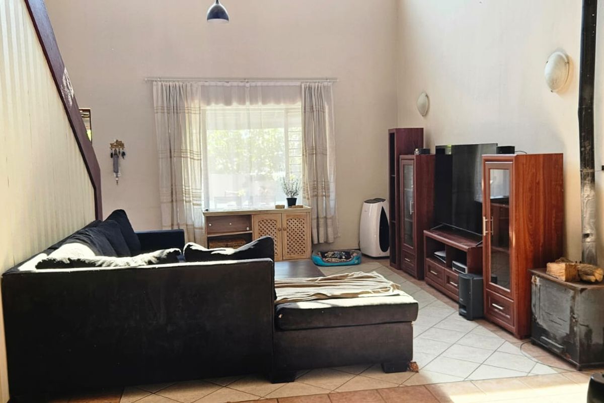 Spacious living room featuring high ceilings, tiled flooring, and a built-in wood-burning fireplace, offering a comfortable and functional layout.