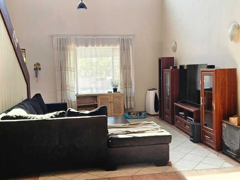 Spacious living room featuring high ceilings, tiled flooring, and a built-in wood-burning fireplace, offering a comfortable and functional layout.