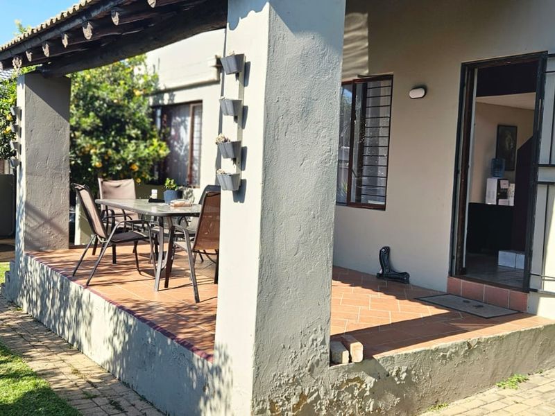A covered outdoor patio area featuring tiled flooring, exposed timber beams, and masonry pillars, providing a functional space for outdoor relaxation.