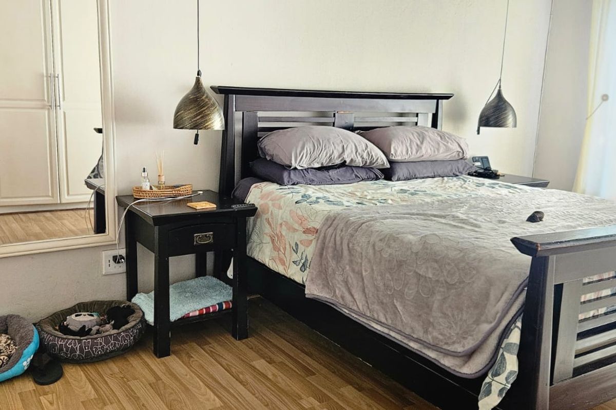 A well-maintained bedroom featuring laminate flooring, built-in wardrobe storage, and modern pendant lighting fixtures.