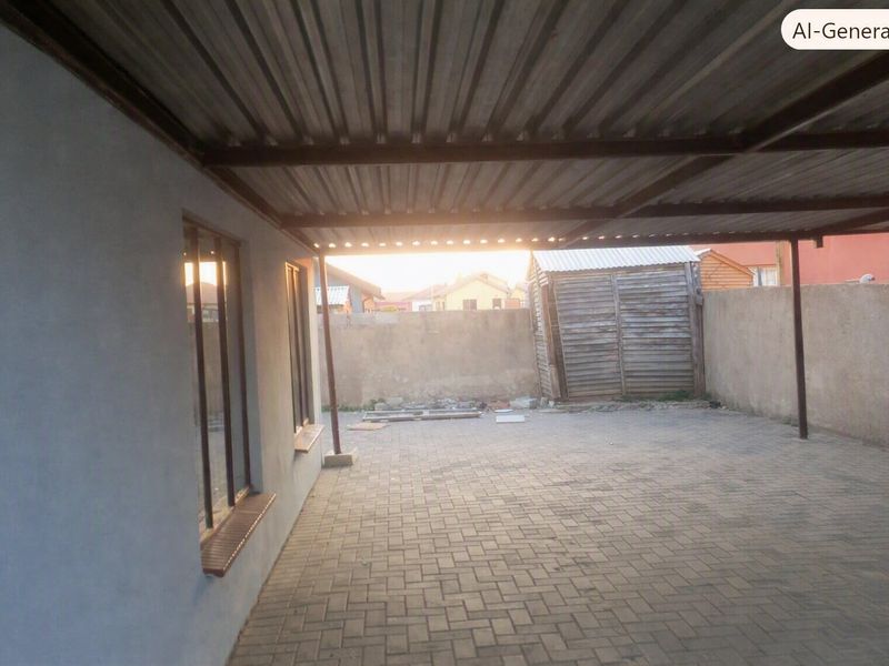 A covered outdoor patio area featuring paved flooring, metal roofing, and a perimeter boundary wall, offering a functional space for outdoor use.