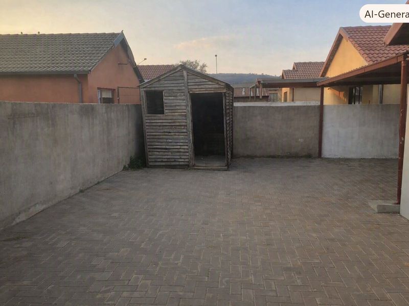 A paved rear courtyard featuring a perimeter boundary wall and a weathered wooden storage shed.