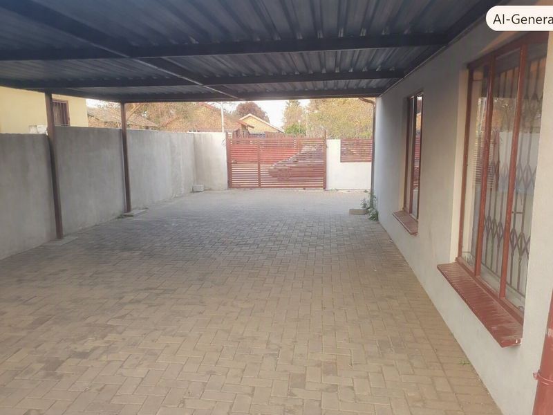A covered carport area featuring paved flooring, a corrugated metal roof, and a secure perimeter wall with a metal gate.